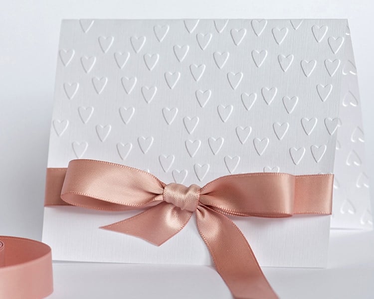 handmade card with embossed hearts and beige bow on white backgr
